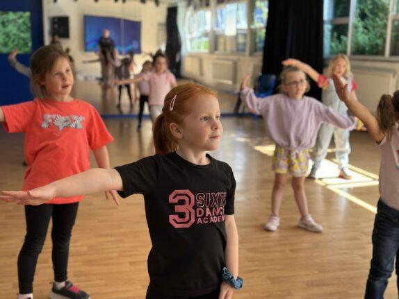 Children learning how to dance in a dance studio. The girl in the centre image is wearing a black top with the 3SIXTY Dance Academy Logo on.